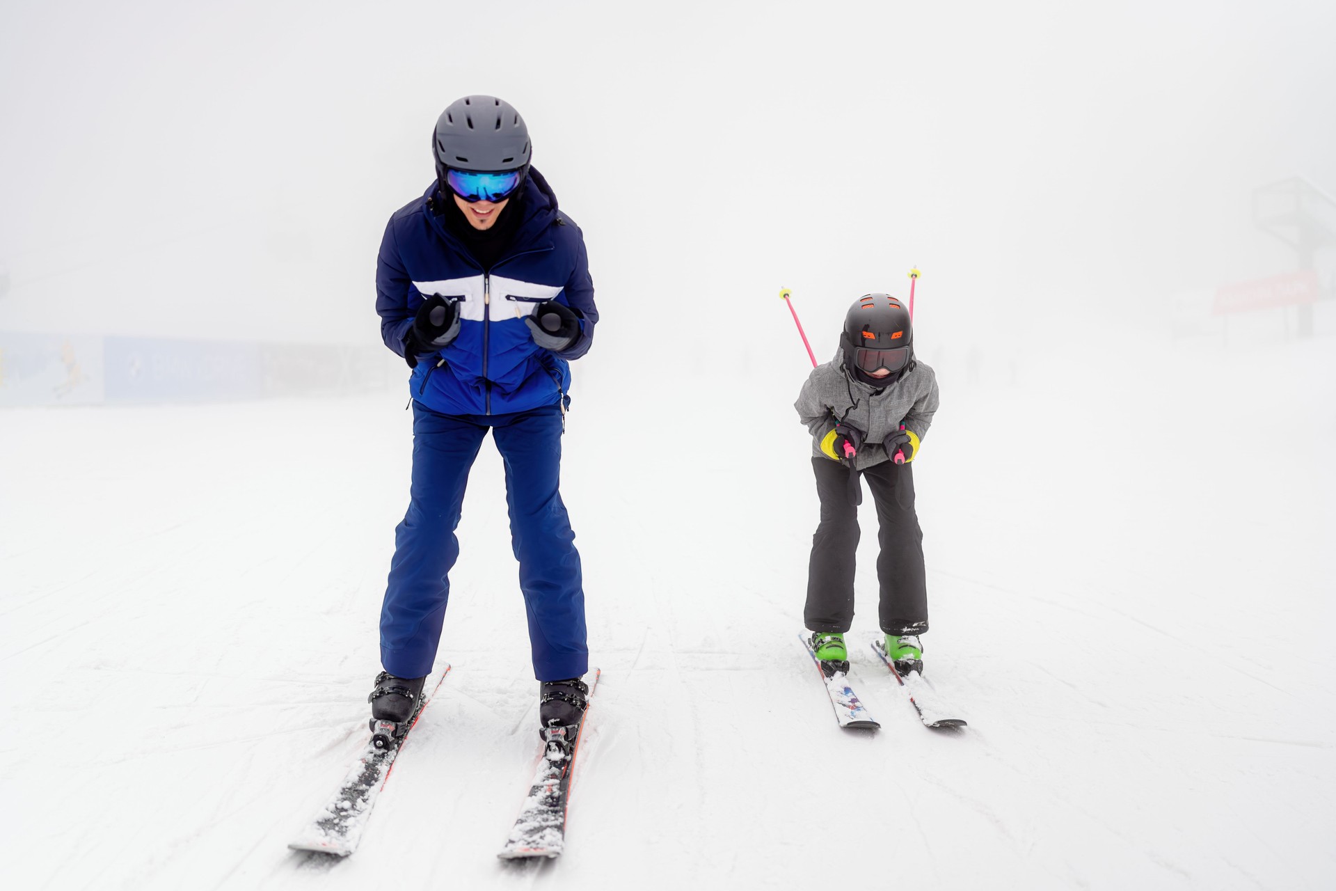 Two skiers enjoying a snowy day on the slopes in dense fog